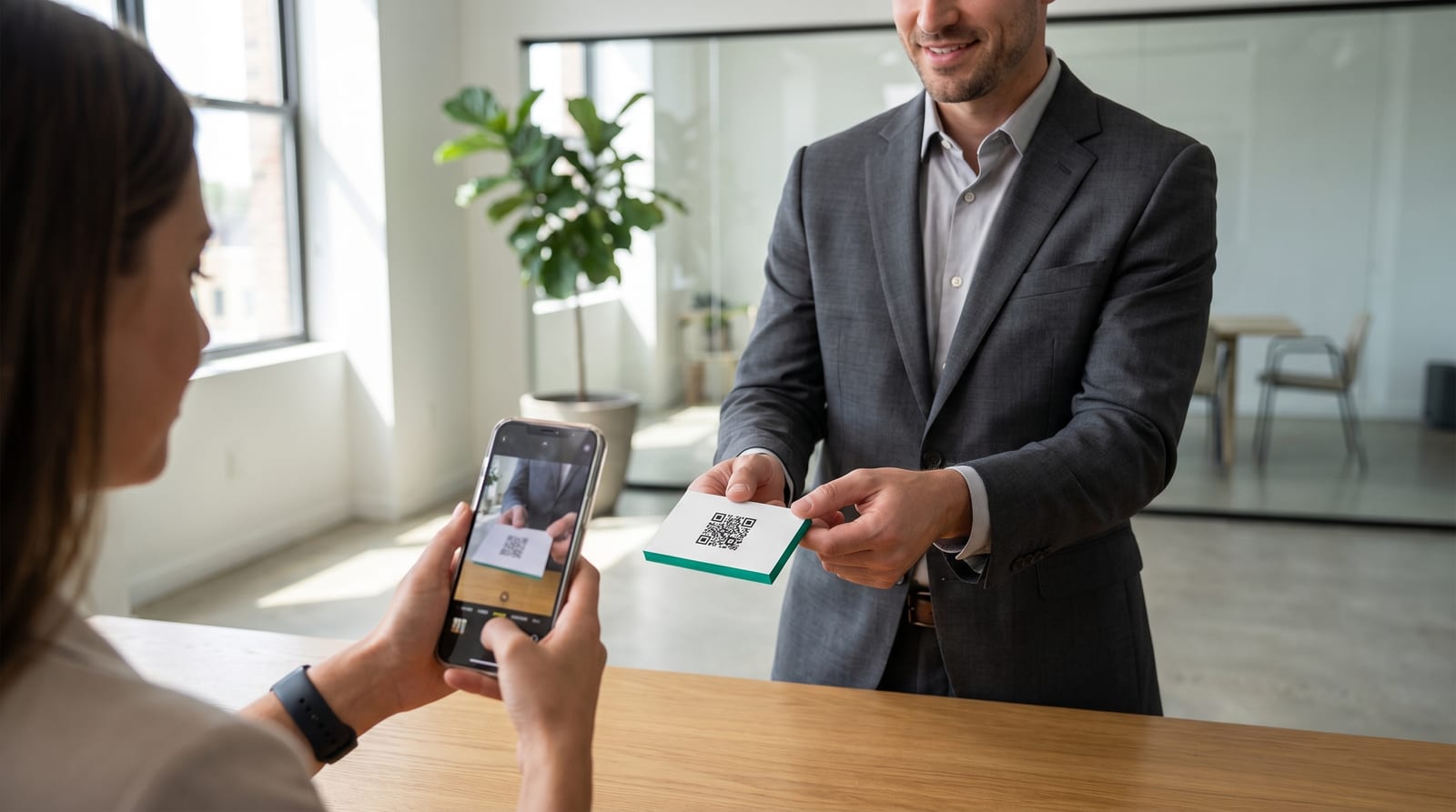 Businessman hands over a minimalist business card with a QR code while a client scans it
